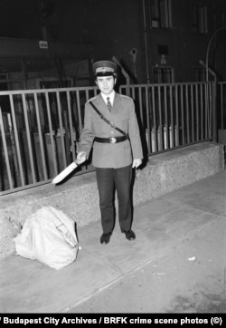 A policeman poses with a large knife, probably at the scene of a crime.