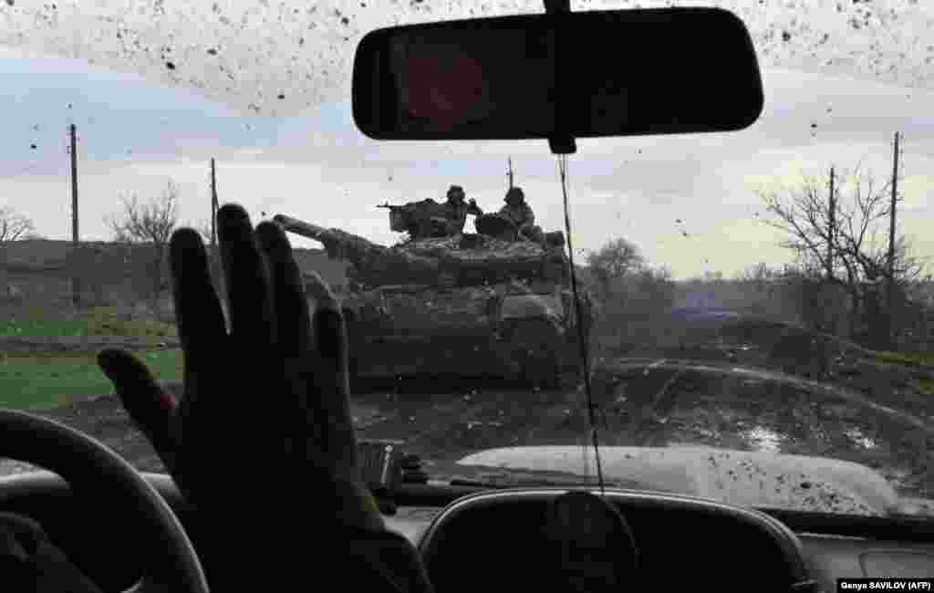 Ukrainian soldiers wave to each other along a road near the city of Bakhmut on April 8. The brutal battle for &quot;Fortress Bakhmut&quot; is being called the bloodiest infantry battle since World War II.