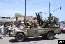 Sudanezii îi salută de pe margine pe soldații loiali șefului armatei Abdel Fattah al-Burhan în orașul Port Sudan, de la Marea Roșie, pe 16 aprilie.