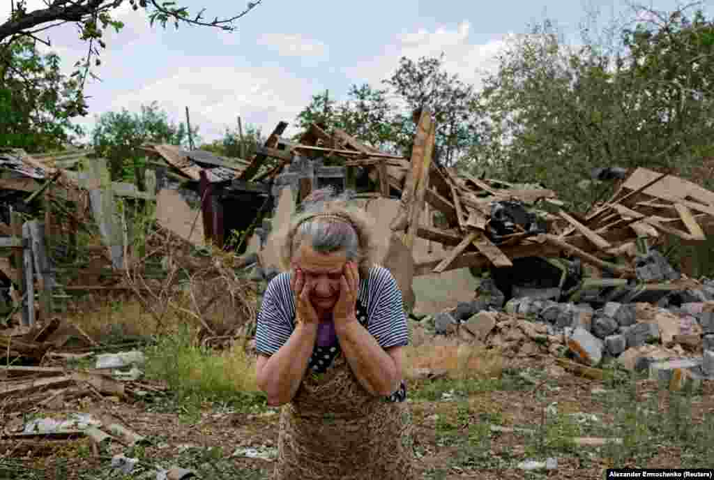Valentina Chernaya, 90 vjeçe, reagon pranë shtëpisë së saj të dëmtuar dhe ndërtesave të shkatërruara pas bombardimeve të fundit në fshatin Rozivka në rajonin e Donjeckut, Ukrainë.