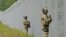 Latvian border guard officers patrol along the fence along the Latvia-Belarus border near Robeznieki, Latvia, on August 8.