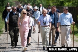 King Charles III (center) walks down a street in the village of Valea Zalanului, 250 kilometers north of Bucharest, during his recent visit to Romania.