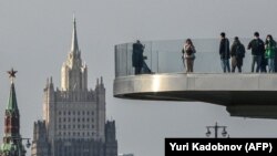 RUSSIA - People walk on a bridge in the Zaryadye park with a Kremlin's tower and Russian Foreign Ministry building in the background, Moscow, October 25, 2021. 