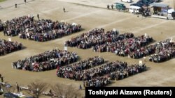Японские протестующие создают послание «НЕ ВОЙНИ! НЕТ DU!» во время митинга против вторжения в Ирак в 2003 году и использования обедненного урана
