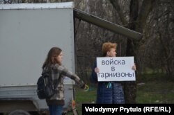 Участницы акции в защиту территориальной целостности Украины держат украинскую символику и плакат "Войска в гарнизоны", протестуя против проведения незаконного референдума в Крыму 16 марта 2014 года.