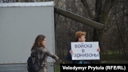 Участницы акции в защиту территориальной целостности Украины держат украинскую символику и плакат "Войска в гарнизоны", протестуя против проведения незаконного референдума в Крыму 16 марта 2014 года.
