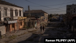 Local residents walk past damaged shops and buildings in Kupyansk, Kharkiv region, on September 28.
