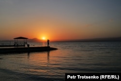 Un bărbat fotografiază apusul soarelui deasupra rezervorului Kairakum, cunoscut și sub numele de Marea Tadjikă.