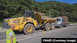 Camion încărcat cu lemne (dreapta) rezultate din defrișări pe Valea Oltului pentru noua autostradă.