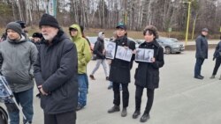 Профессор Сергей Красильников (слева) и два студента НГУ с фото якутского диссидента Платона Ойумского на митинге памяти политзаключенных, Новосибирск, 30 октября 2023 года