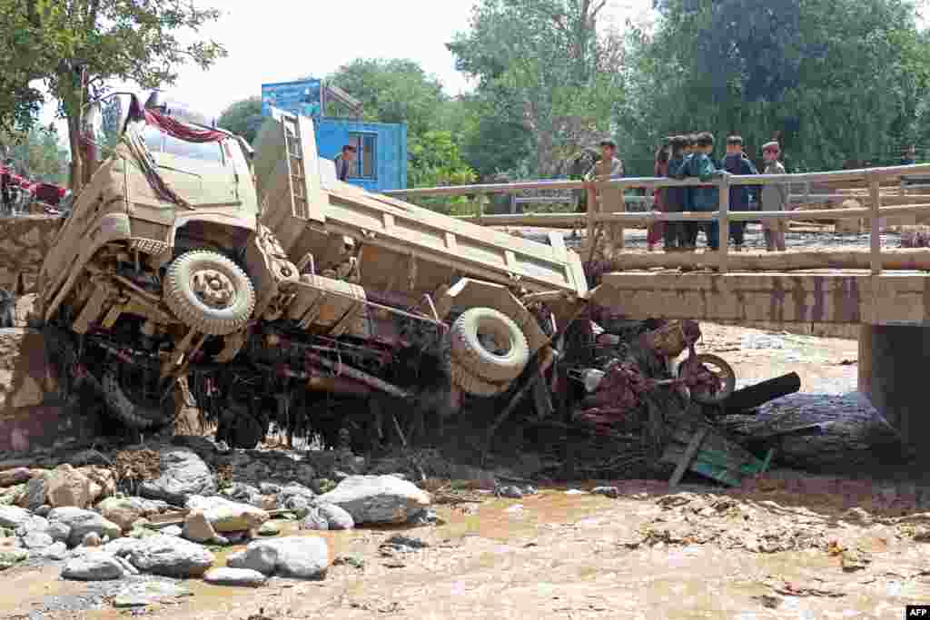 Disa djem afganë shikojnë një kamion që u godit nga përmbytjet në rrethin Jalrez të provincës. Shafiullah Rahimi, zëdhënës i Ministrisë së talibanëve për Menaxhimin e Fatkeqësive, tha më 23 korrik se të paktën 41 persona rezultojnë të zhdukur dhe 74 të plagosur.