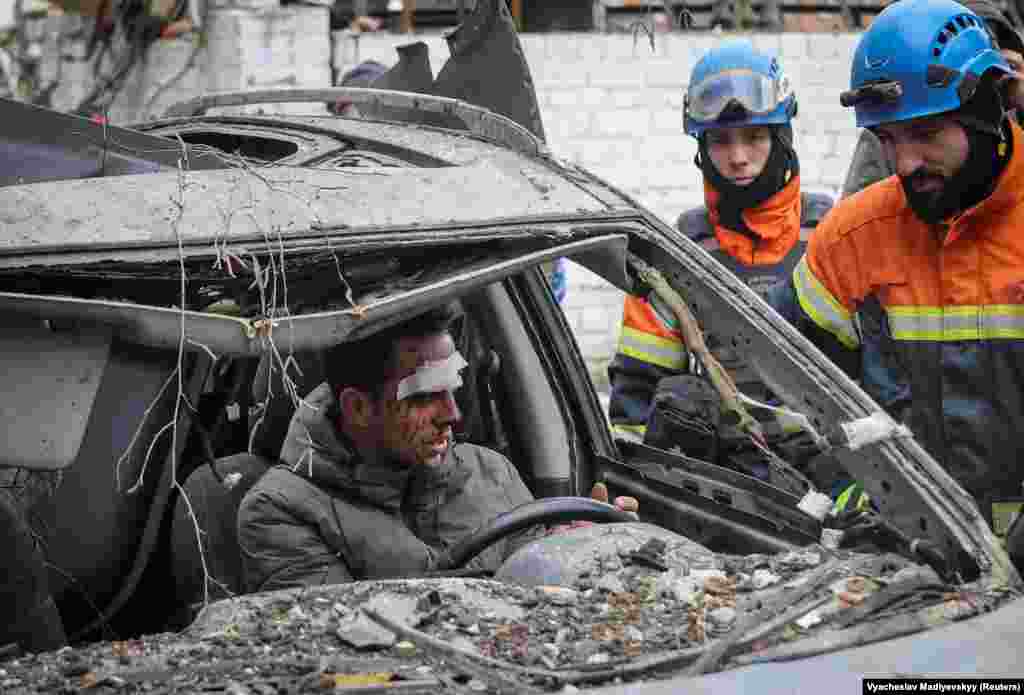 Жител на Харков оглежда унищожената си кола пред жилищна сграда в града след атаката.