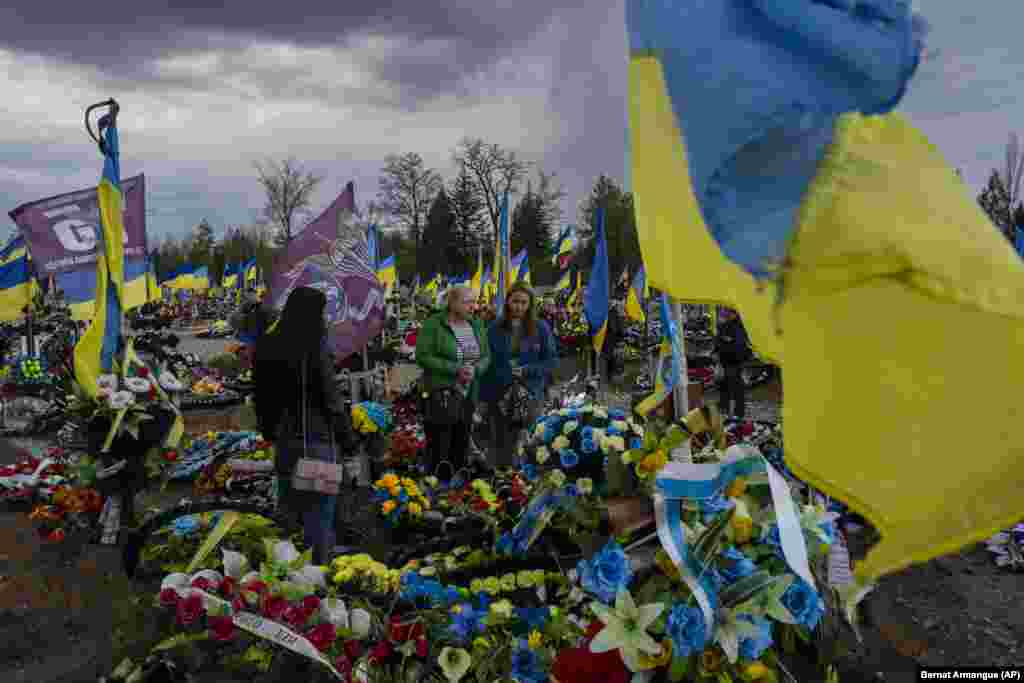 Miqtë dhe familjarët e vizitojnë varrin e një ushtari të vrarë ukrainas në ceremoninë e Krivi Rih në lindje të Ukrainës në prill 2023. Ukraina e ka pranuar se 31.000 ushtarë të saj janë vrarë në konflikt, edhe pse ekspertët e pavarur thonë se numri është shumë më i lartë.