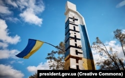 Флаг Украины на стеле с надписью «Купянск» на въезде в город после освобождения ВСУ, 14 сентября 2022 года