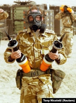 Британский солдат держит подкалиберные снаряды, изготовленные из обедненного урана, для танков «Челленджер-2» во время вторжения США в Ирак в 2003 году.