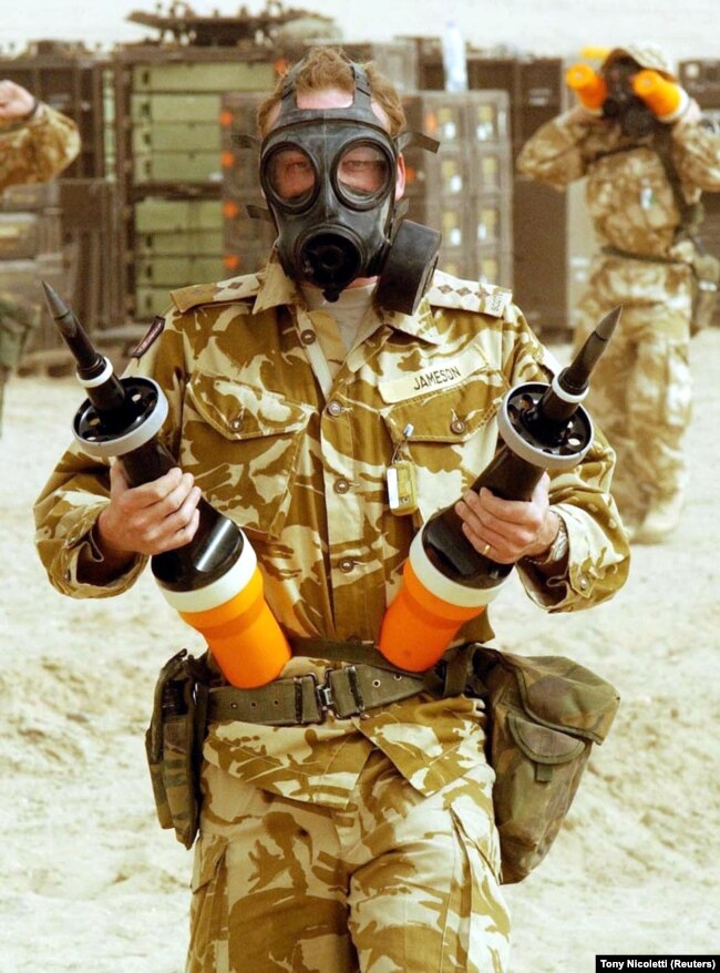 Британски войник държи два кинетични боеприпаса с обеднен уран за танкове Challanger. Снимката е от 2003 г. по време на инвазията на САЩ в Ирак