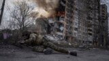 A Ukrainian police officer takes cover in front of a burning building that was hit in a Russian air strike in Avdiyivka on March 17
