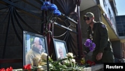 Мъж поднася цветя пред снимките на Евгени Пригожин и Дмитрий Уткин, поставени пред местния офис на паравоенната групировка "Вагнер" в Новосибирск. Твърди се, че двамата са загинали в самолетна катастрофа в сряда.