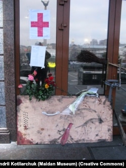 Двері готелю «Україна», кінець лютого 2014 року. На прикріпленому аркуші список загиблих майданівців, яких принесли сюди з вулиці Інститутської