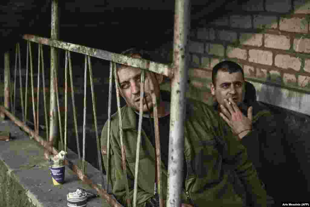 Ukrainian soldiers smoke a cigarette at the entrance to their basement shelter.