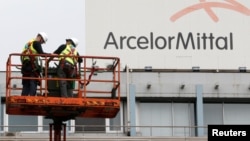 Рабочие на фоне логотипа компании «АрселорМиттал». Иллюстративное фото