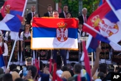 Serbian President Aleksandar Vucic shows a Serbian flag during the "All-Serb Assembly" in Belgrade on June 8.