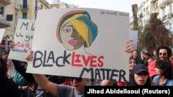 Detalj sa protesta u glavnom gradu Tunisa, 25. februar 2023. Jedna od učesnica protesta nosi transparent na kome piše "Životi crnaca su važni". 