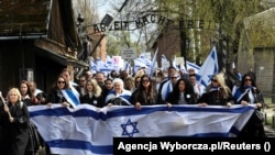 Učesnici Marša prolaze pored kapije sa ciničnim napisom "Rad oslobađa" preko najvećeg logora koji su njemački nacisti podigli u okupiranoj Poljskoj, Auschwitz, 18. april 2023.