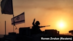 Израильский солдат выглядывает из танка, недалеко от границы Израиля с сектором Газа, на юге Израиля, 12 октября 2023 года