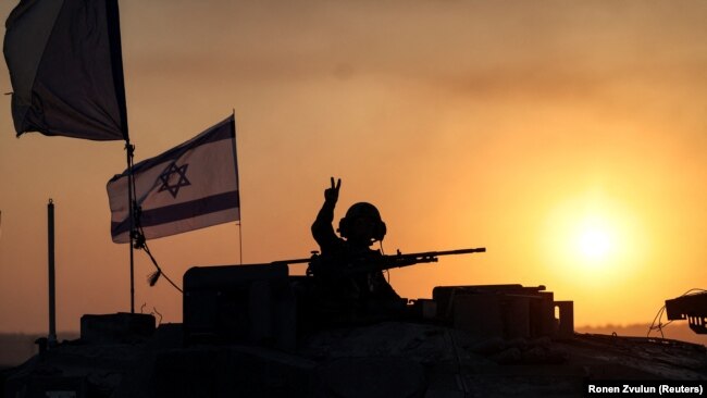 Израильский солдат выглядывает из танка, недалеко от границы Израиля с сектором Газа, на юге Израиля, 12 октября 2023 года