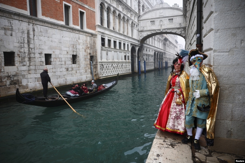 Pjesëmarrësit të maskuar me kostume të veçanta në Karnavalin e Venedikut pranë urës Ponte de Sospiri në Venedik, Itali.