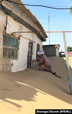 Mamyrova shows the doorway to her outbuilding that is blocked with sand.