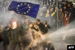 Protesters holding an EU flag are hit with a water cannon during a protest on March 7 outside parliament in Tbilisi after legislators gave preliminary backing to a bill that would require organizations with a certain amount of funding from abroad to register as "foreign agents."