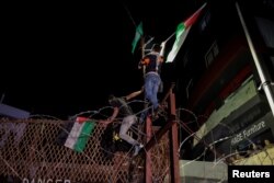 Manifestanți libanezi flutură steaguri palestiniene în timp ce escaladează gardul ambasadei SUA din Beirut, Liban, 17 octombrie 2023.