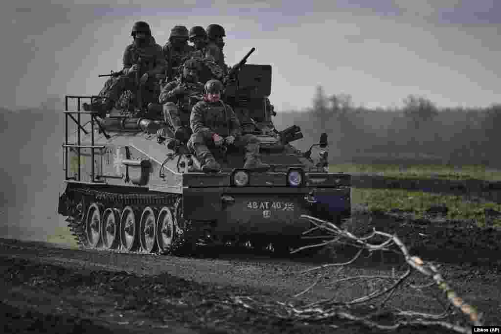 Ukrainian soldiers at the front ride atop an APC. &nbsp;