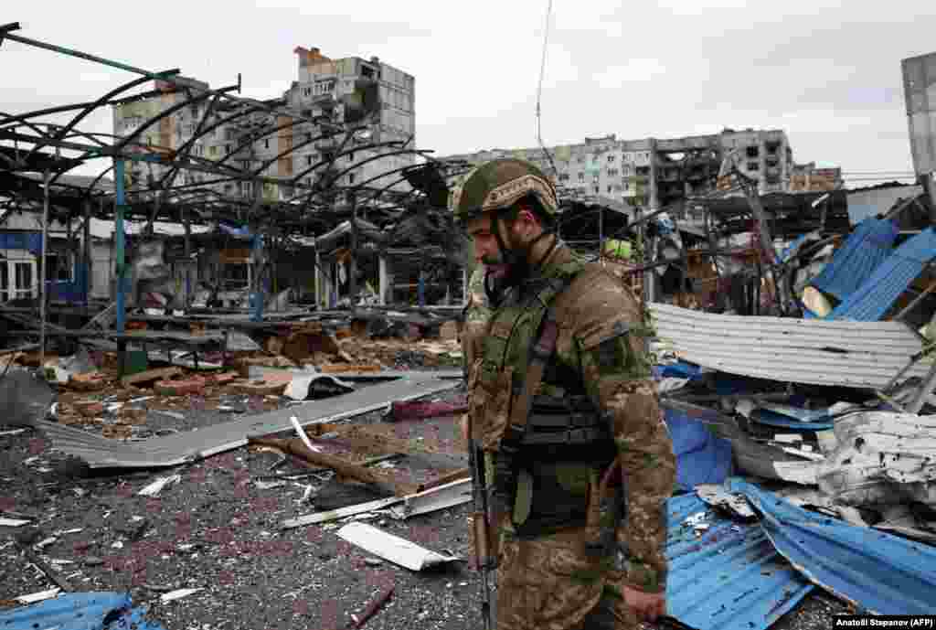 Un soldat ucrainean se plimbă pe lângă clădirile rezidențiale din Bahmut, avariate de bombardamente.