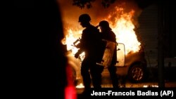 Zyrtarë policorë, pranë një veture në zjarr në Strasburg të Francës, 30 qershor 2023.