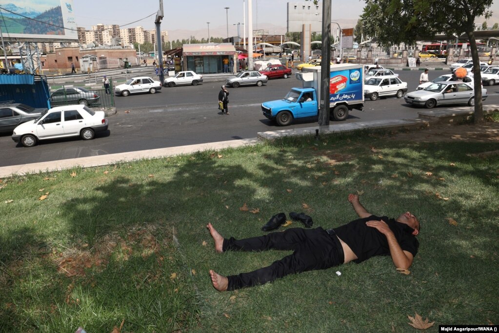Un uomo riposa all'ombra vicino a una strada trafficata a Teheran.  Il ministero della Salute ha anche avvertito che potrebbe essere necessario estendere la chiusura di due giorni per proteggere la salute delle persone.