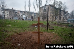 Хрест на могилі загиблого від російського обстрілу місцевого жителя у дворі житлового будинку, 12 квітня 2023 року