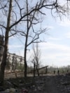 Люди стоять між будинками, які були зруйновані артилерійським обстрілом і авіаударами в Очеретиному неподалік від Авдіївки Донецької області, 15 квітня 2024 року