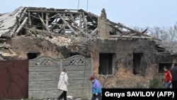 یوشمېر وګړي په کوستیانتېنیفکا کې د اپرېل پر دویمه د روسیې په بمبارۍ کې د زیانمنې ودانۍ مخې ته تېږېږي. 