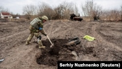 A Ukrainian serviceman buries the remains of what he said was the dead body of a Russian soldier in a village near Kyiv that was reclaimed by Ukraine in March 2022. 