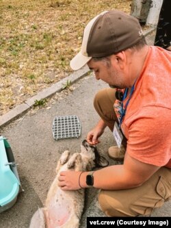 Leonid pets a dog rescued from flooding in Kherson.