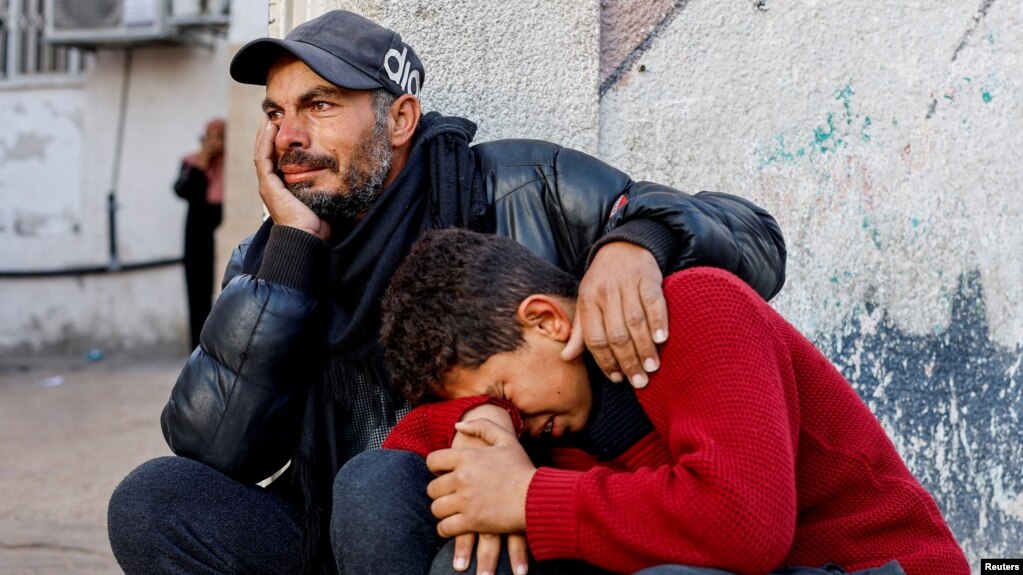 Një burrë dhe një djalë qajnë për palestinezët e vrarë në sulmet izraelite në spitalin Abu Yousef Al-Najjar.