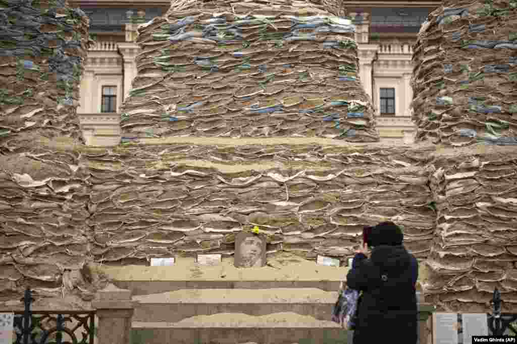 A woman takes pictures of the statue of Grand Princess Olga of Kyiv, covered in sandbags to avoid damage from potential shelling, in Kyiv.