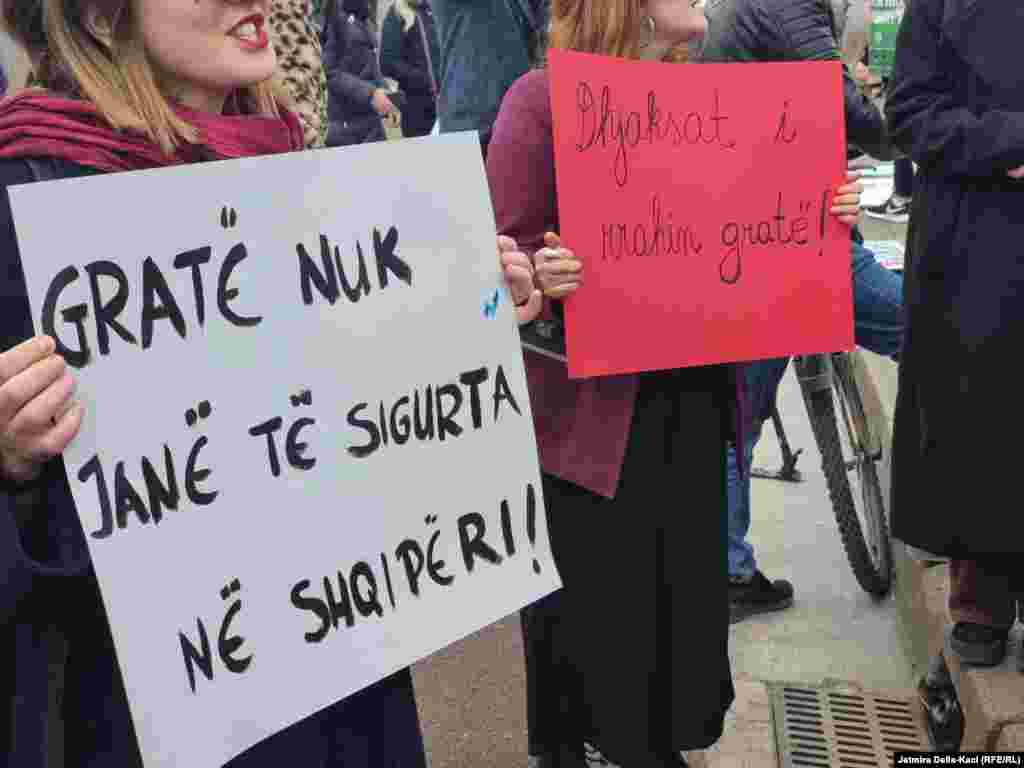 Një grua duke mbajtur një pankartë me mbishkrimin &quot;Gratë nuk janë të sigurta në Shqipëri&quot;.