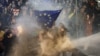 Protesters brandishing a European Union flag are sprayed by a water cannon during demonstrations against the bill in Tbilisi on March 7, 2023.