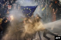 Protesters brandishing an EU flag are sprayed by a water cannon during clashes with riot police near the Georgian parliament in Tbilisi on March 7. Thousands of people took to the streets of the capital to oppose a controversial "foreign agents" bill.