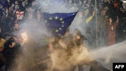 Protesters brandishing a European Union flag are sprayed by a water cannon during demonstrations against the bill in Tbilisi on March 7, 2023.