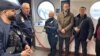 Қидирувдаги шахсни Ўзбекистонга экстрадиция қилиш пайтида олинган фотосурат. ИИВ сайтидан олинди.